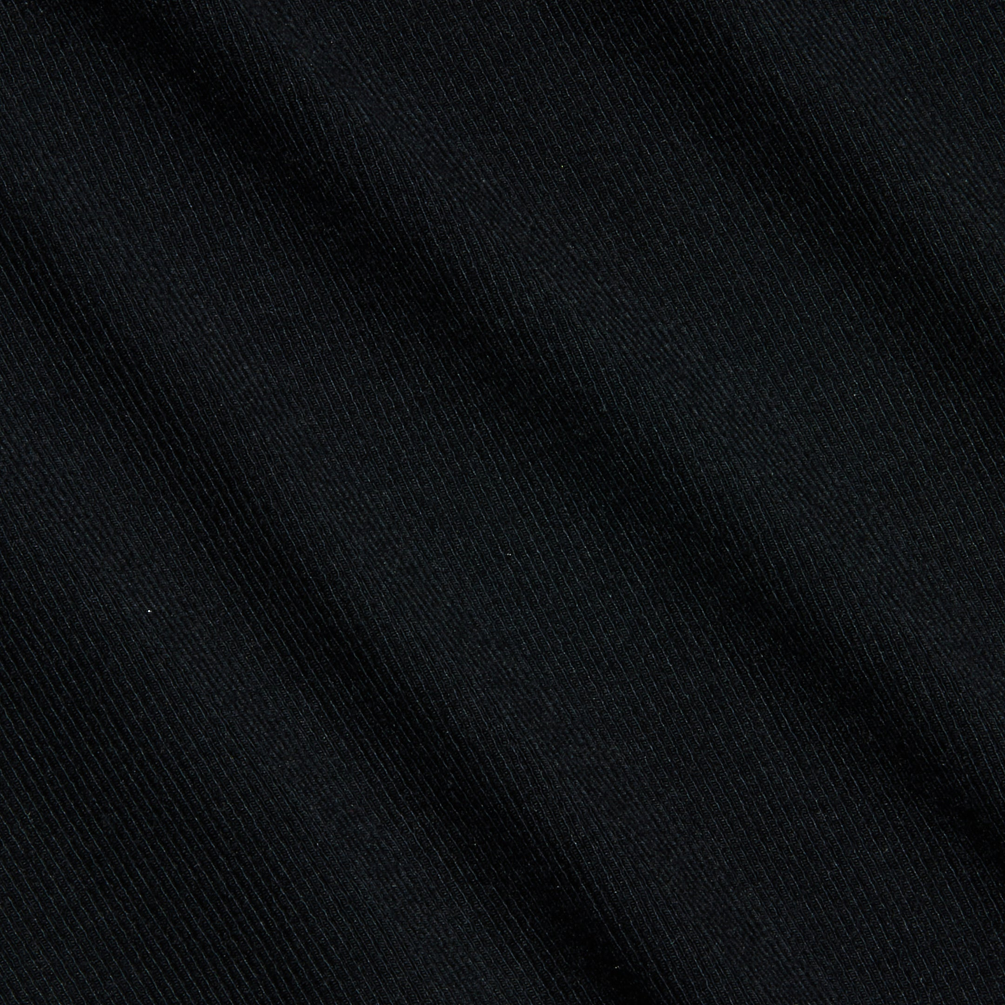 Close-up of the Wrenna Racerback Bodysuit in black rib fabric, featuring a subtle diagonal texture and fine visible lines that create a soft, slightly wavy pattern across the surface.