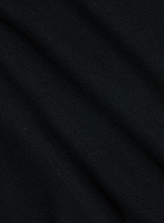 Close-up of the Wrenna Racerback Bodysuit in black rib fabric, featuring a subtle diagonal texture and fine visible lines that create a soft, slightly wavy pattern across the surface.