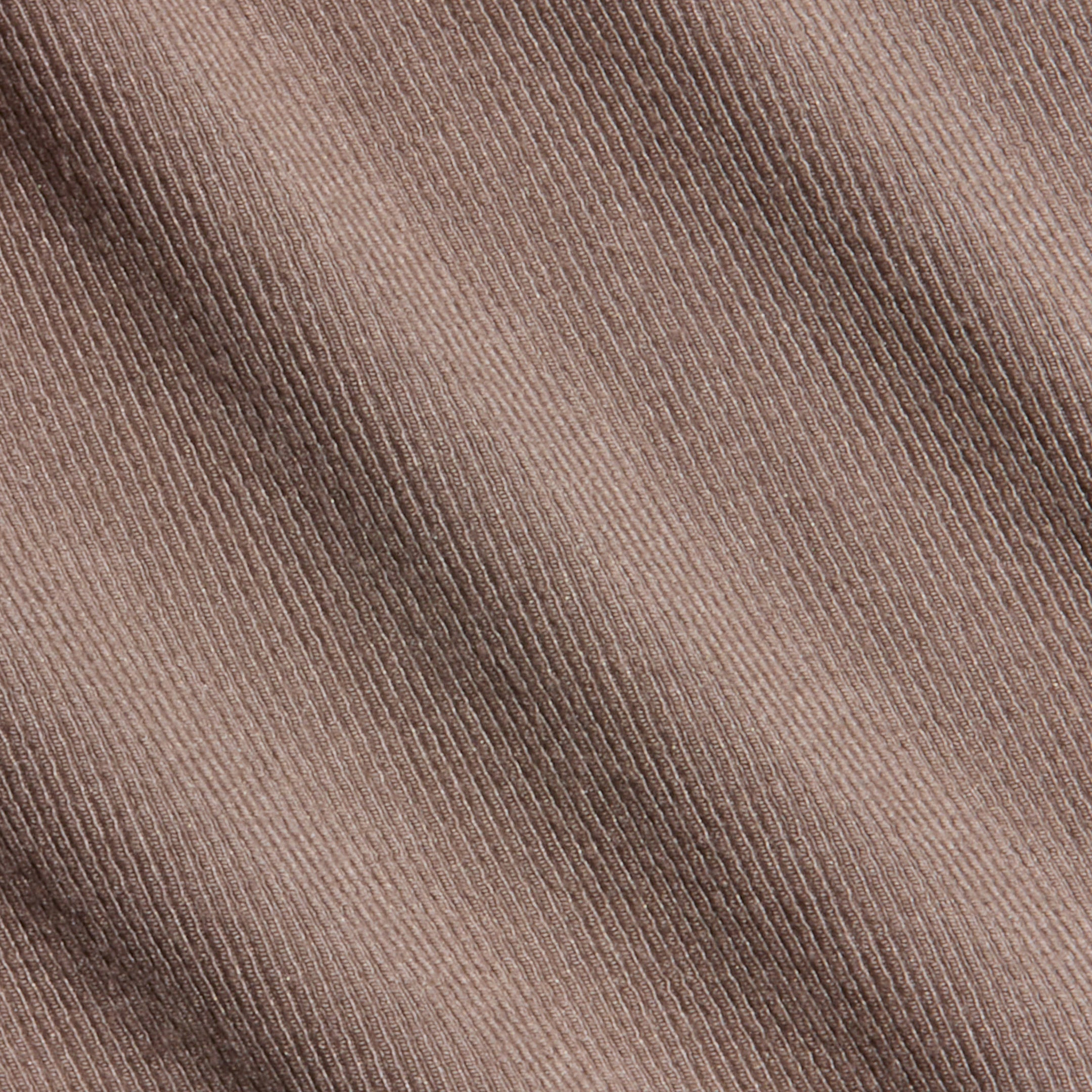 Close-up of the Wrenna Racerback Bodysuit’s brown corduroy fabric, showcasing its diagonal ribbed texture and fine weaving detail, reminiscent of rib fabric.