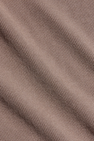 Close-up of the Wrenna Racerback Bodysuit’s light brown, diagonally ribbed fabric, highlighting its fine weave lines and subtle shadows across the material.