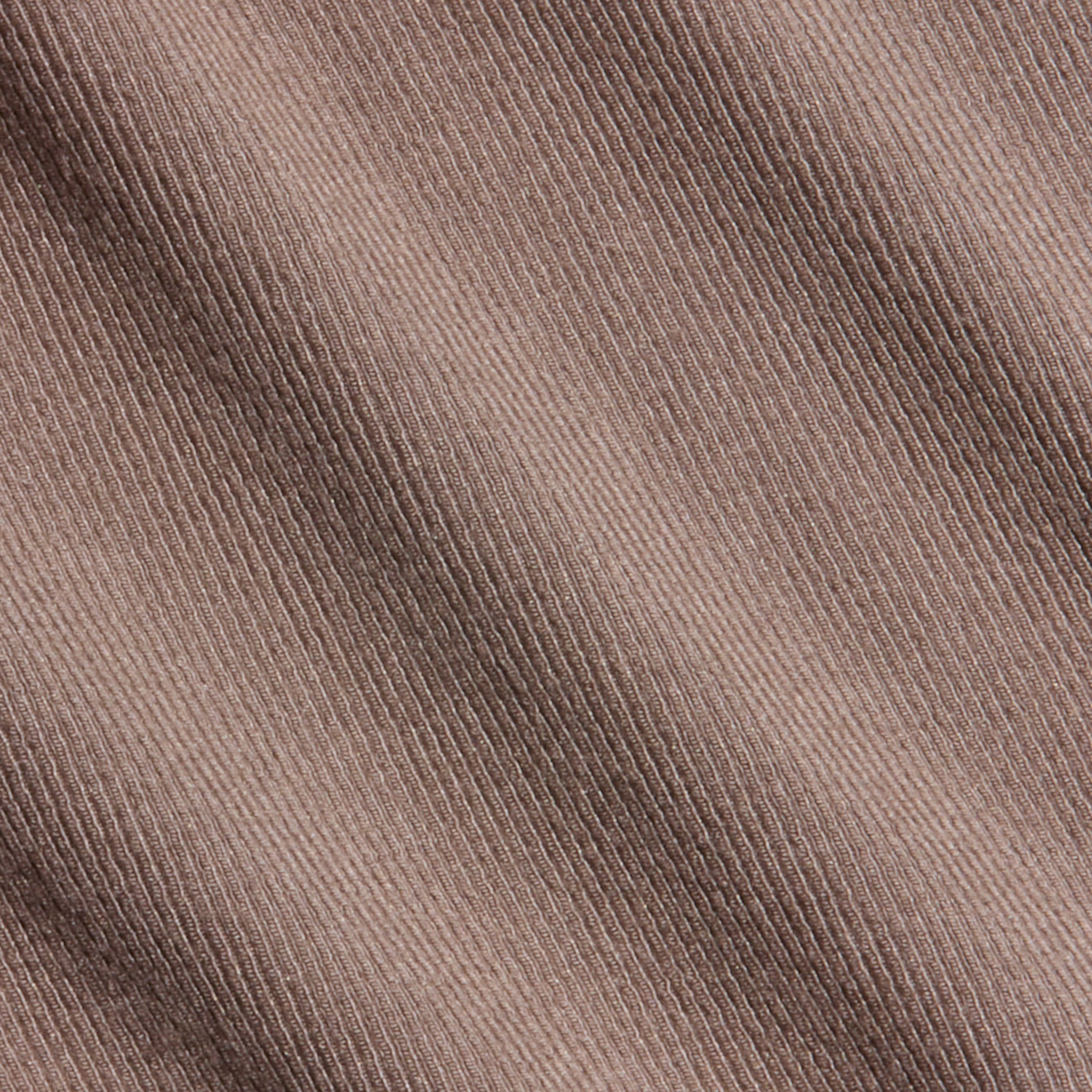Close-up of the Wrenna Racerback Bodysuit’s brown corduroy fabric, showcasing its diagonal ribbed texture and fine weaving detail, reminiscent of rib fabric.