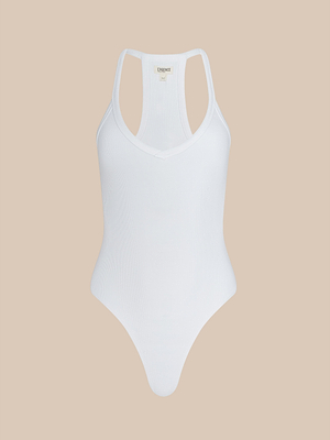 The Wrenna Racerback Bodysuit features a white fitted design with a scoop neckline, high-cut legs, and soft rib fabric, shown against a plain beige background.