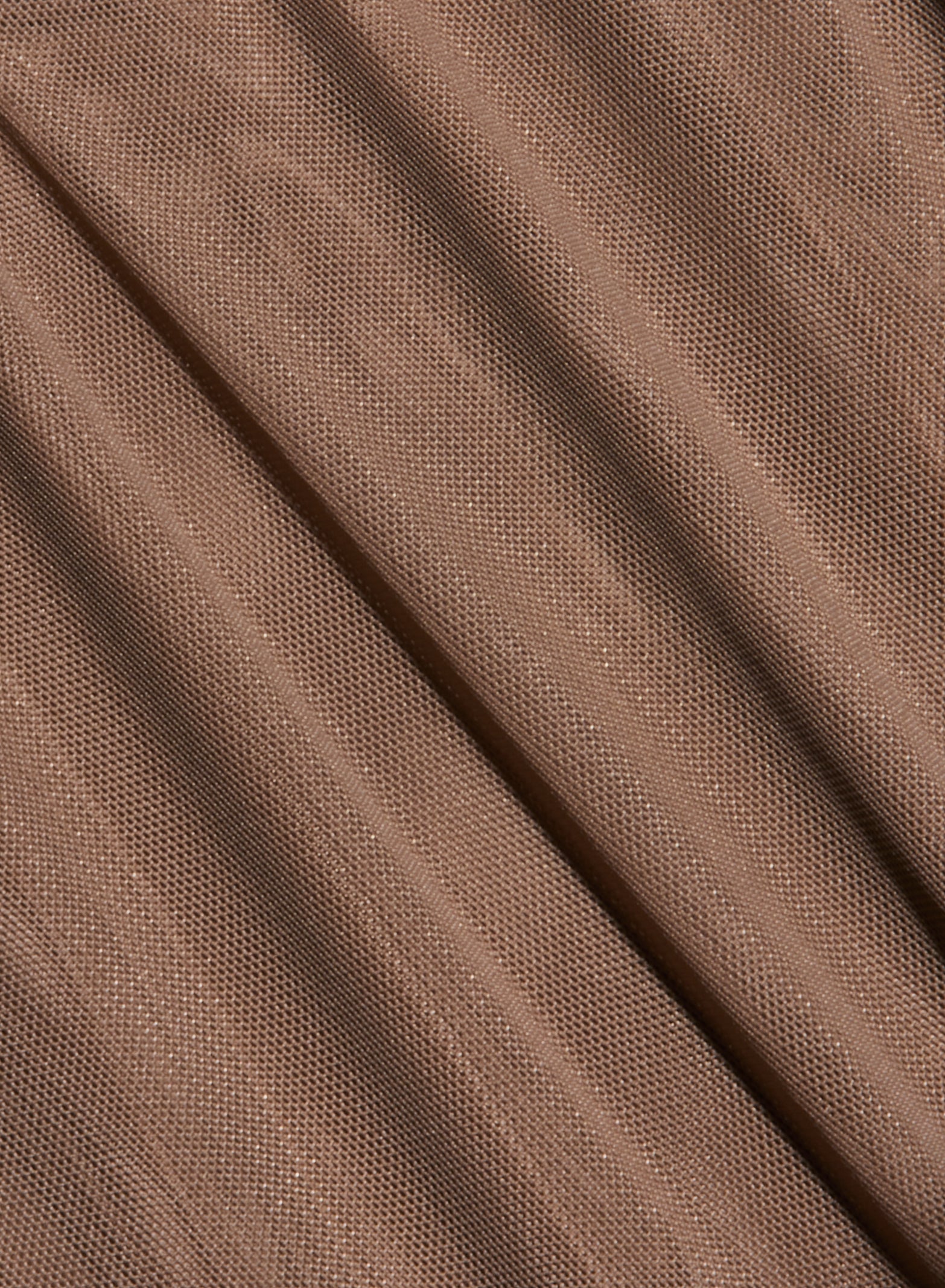 Close-up of the Thalassa High-Leg Bodysuit, featuring light brown mesh fabric with a fine, net-like texture and diagonal folds that create shadowed lines across the surface, evoking chic French style.