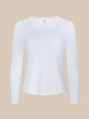 The Rojene Cotton Tee, a plain white long-sleeve shirt made from Supima cotton, is shown on a beige background. It features a simple, fitted design with no visible patterns or embellishments.