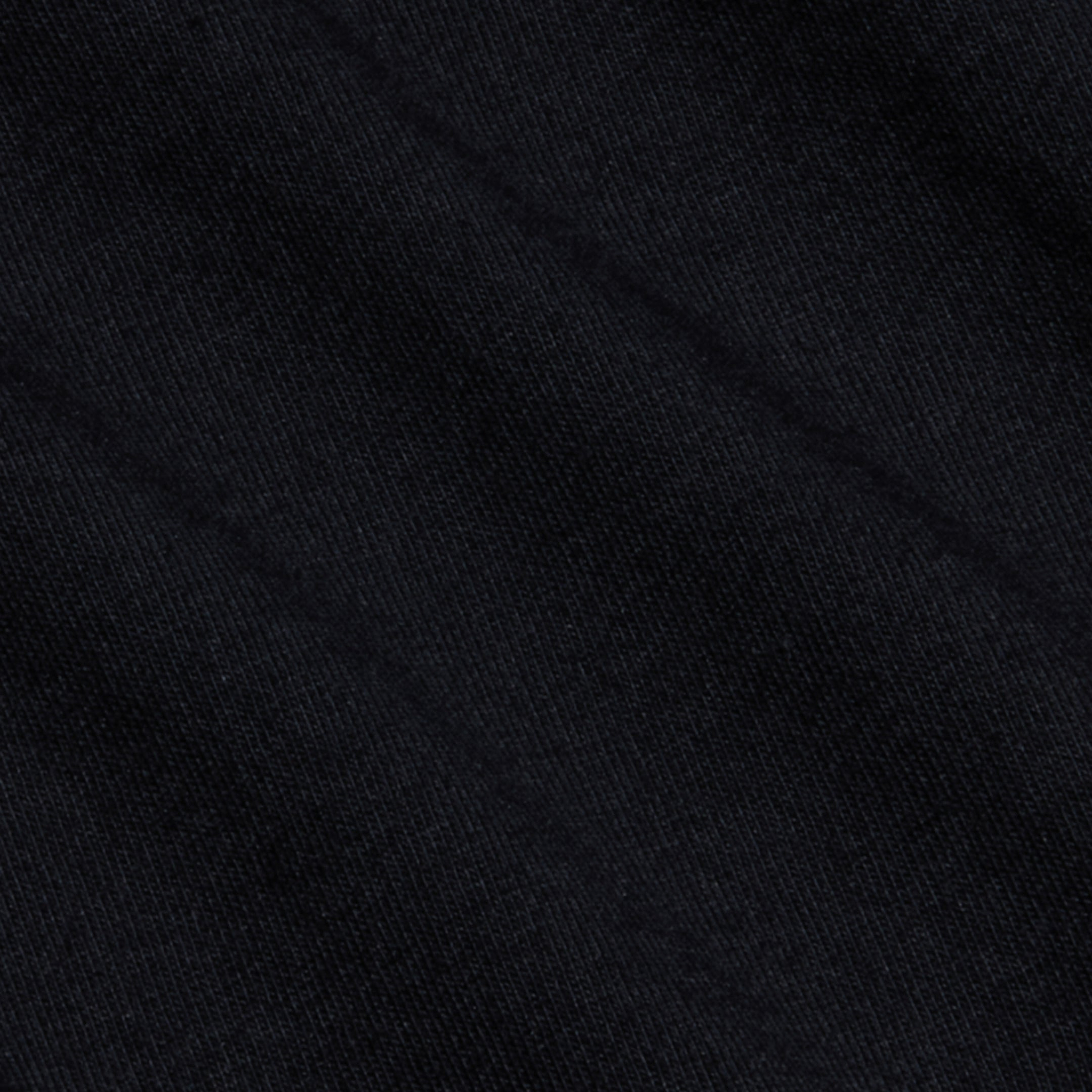 Close-up of a black textured fabric with subtle diagonal lines and shadows, displaying fine woven fibers and a soft surface pattern—crafted from luxurious Supima cotton, as featured in the Brianna Cotton V-Neck Tee.