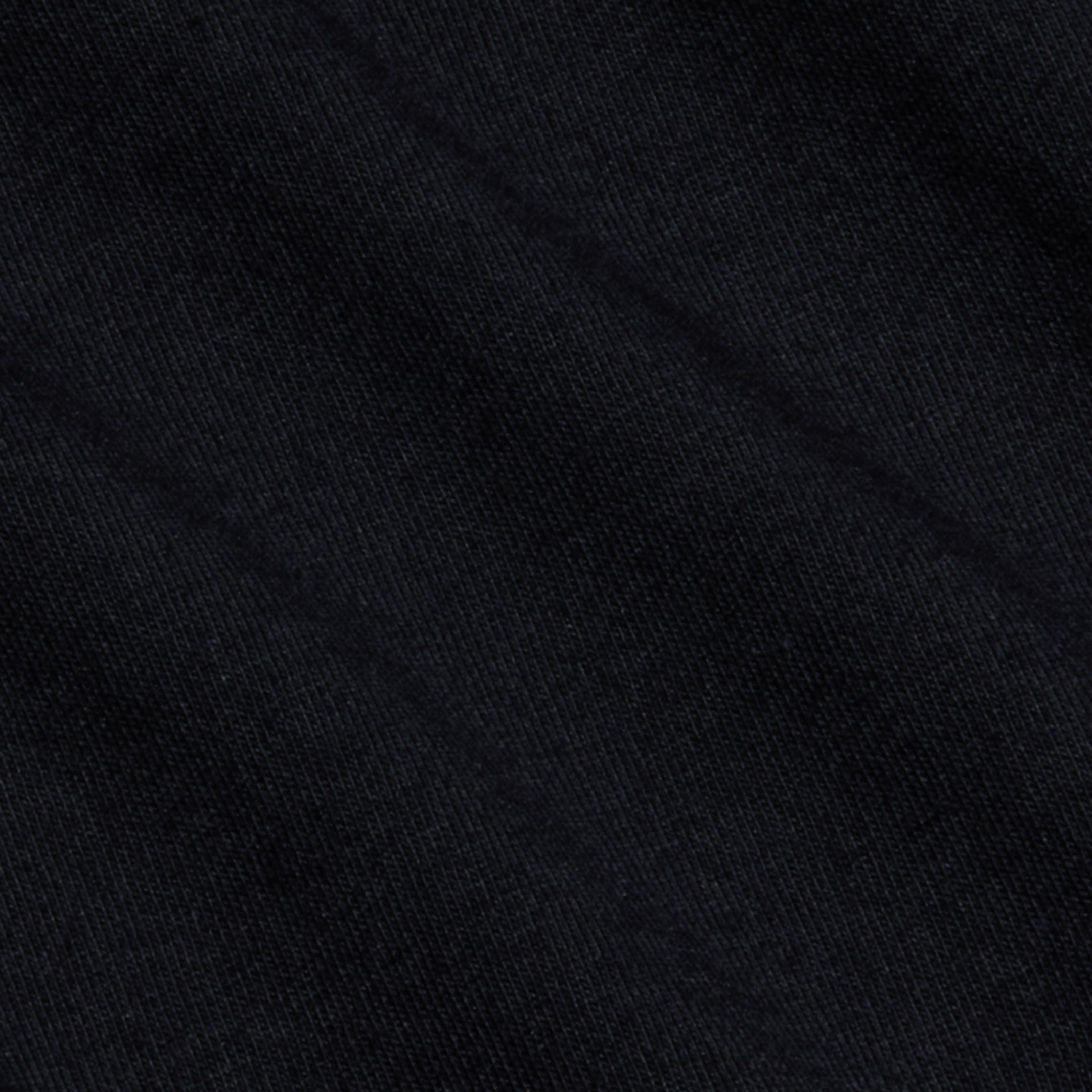 Close-up of a black textured fabric with subtle diagonal lines and shadows, displaying fine woven fibers and a soft surface pattern—crafted from luxurious Supima cotton, as featured in the Brianna Cotton V-Neck Tee.