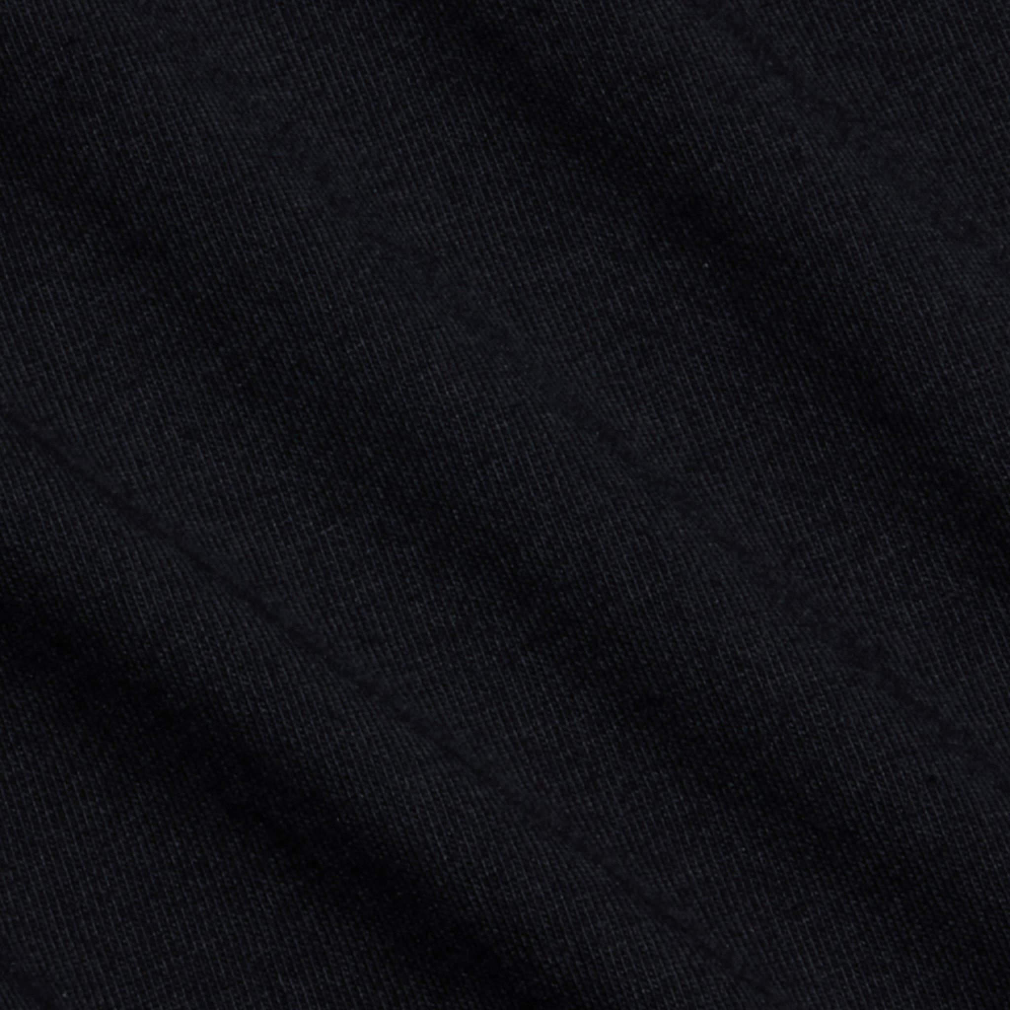 Close-up of black Supima cotton fabric with a subtle diagonal pattern and visible texture, showcasing fine threads and soft folds—ideal for the comfortable fit of the Aileen Cotton Crewneck Tee.