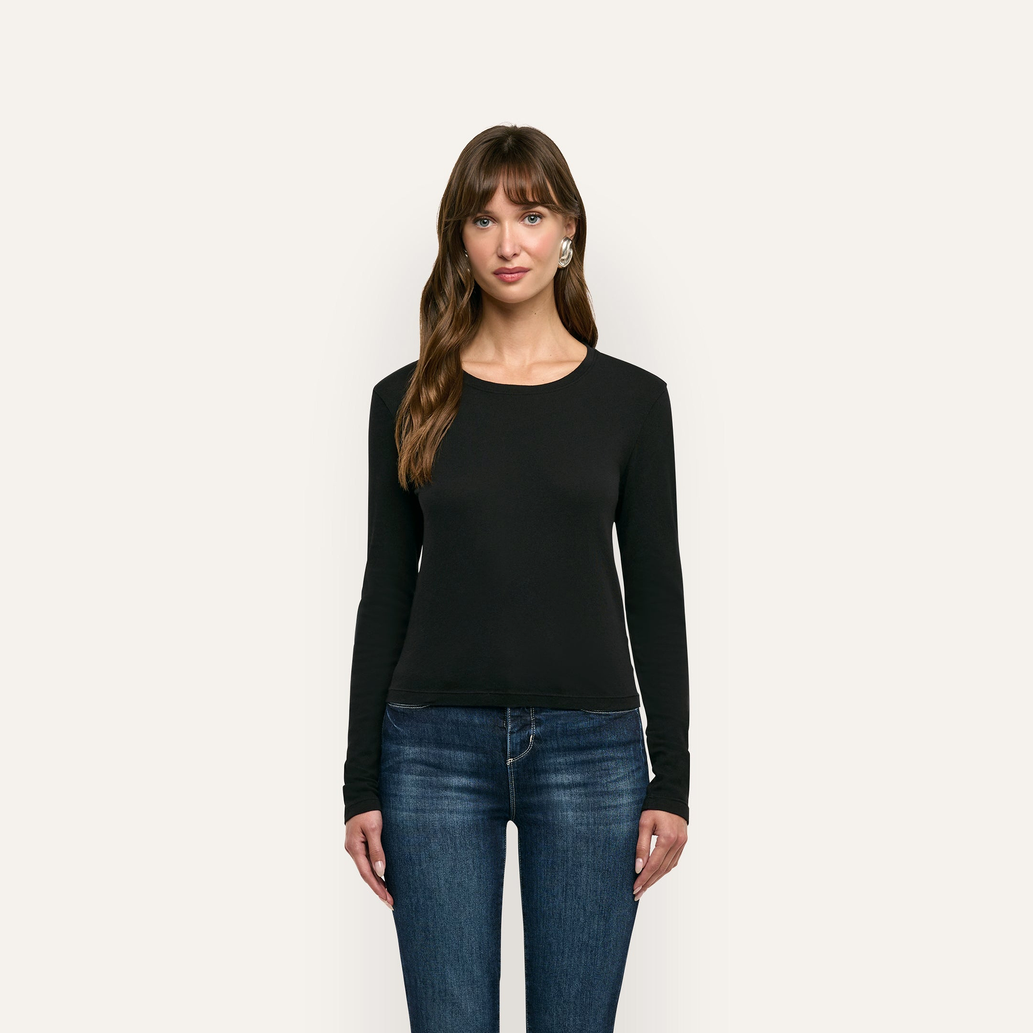 A woman wearing a black long-sleeved Leanne Cotton Tee and blue jeans.
