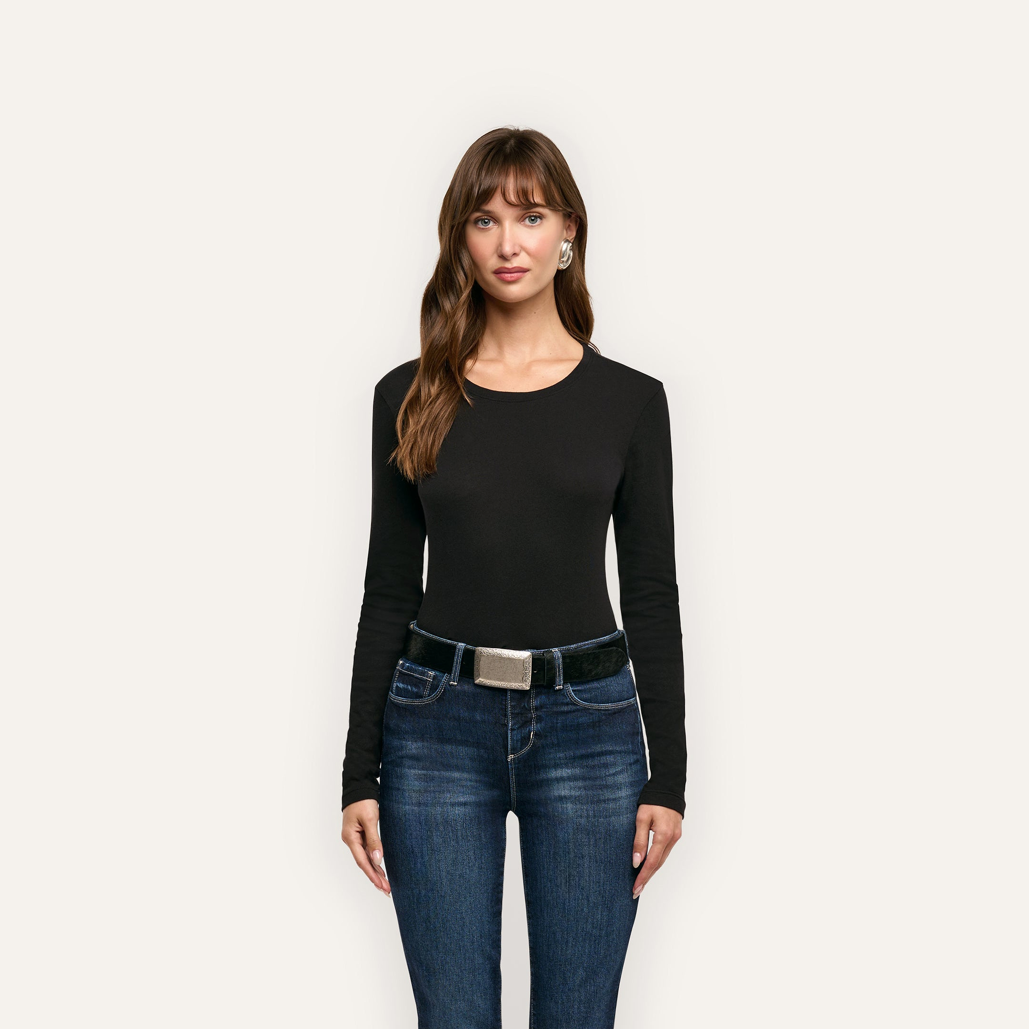 Woman wearing a black Leanne Cotton Tee long-sleeved crewneck and blue jeans with a black belt.