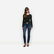 A woman wears a black Leanne Cotton Tee tucked into dark wash skinny jeans with a black belt and black high heels.