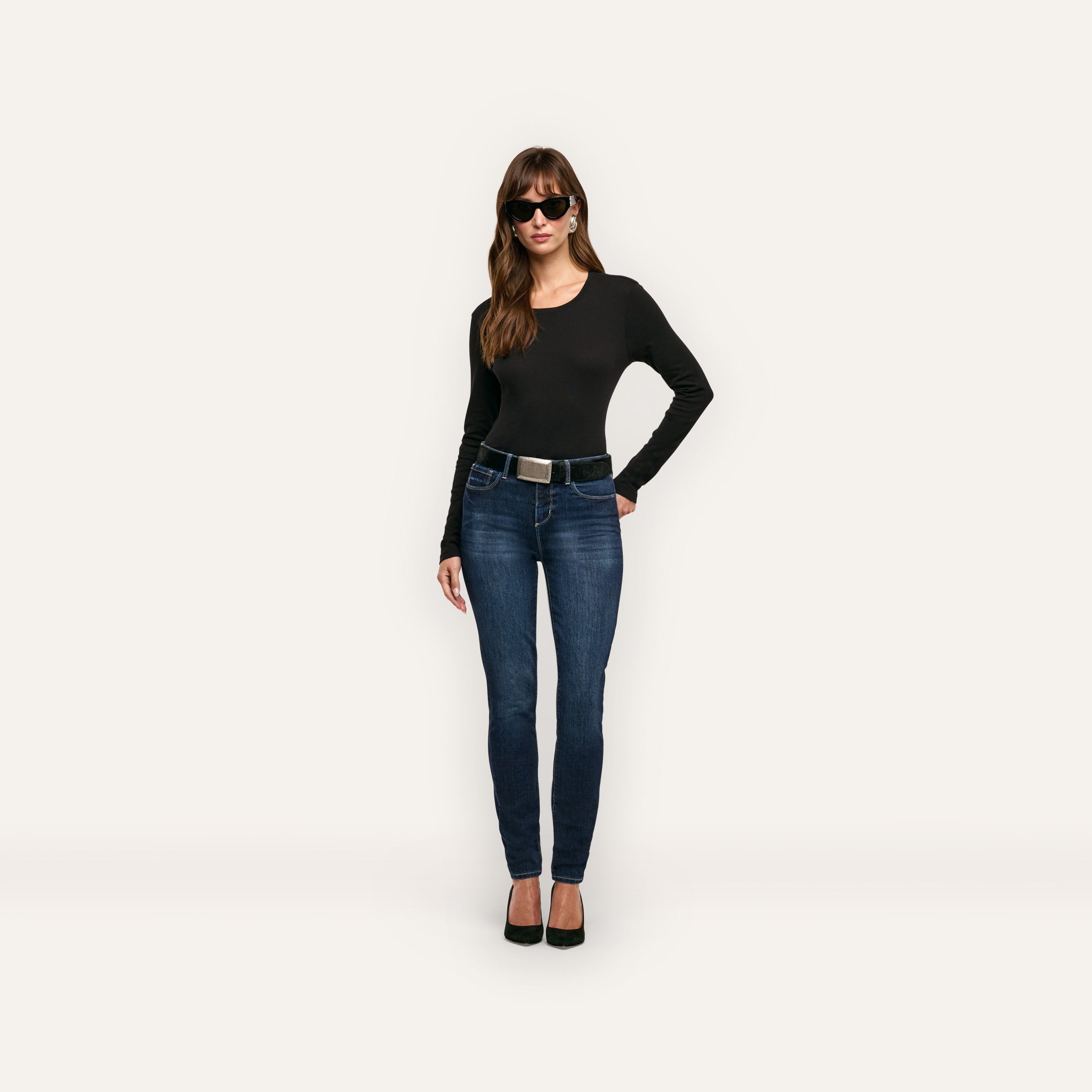 A person wearing a black Leanne Cotton Tee, blue jeans with a black belt, and black sunglasses.