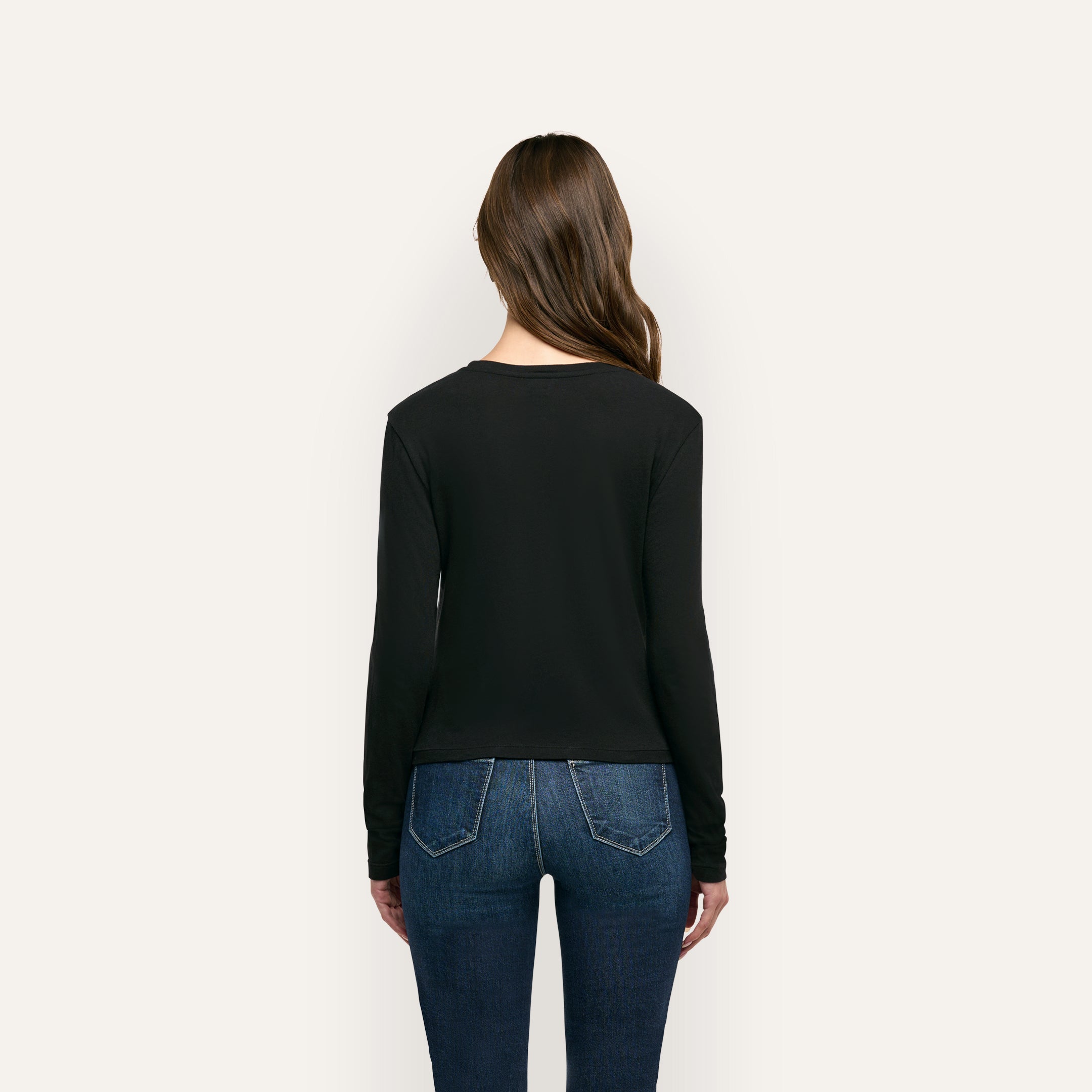 Back view of a person wearing a black organic cotton Leanne Cotton Tee and blue jeans.