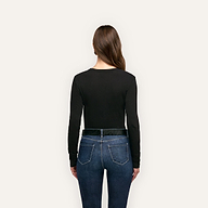 Back view of a person wearing a black long-sleeved Leanne Cotton Tee tucked into blue jeans with a black belt.