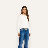 A woman wearing a white Leanne Cotton Tee tucked into blue jeans with a black belt.