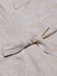Close-up of the Cameron Silk Shirt Dress in light beige and cream paisley print crepe de chine fabric, featuring a soft texture and a tied knot accent at the center.