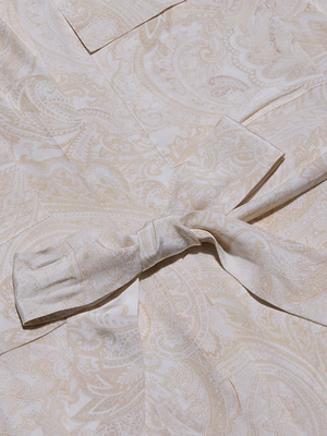 Close-up of the Cameron Silk Shirt Dress in light beige and cream paisley print crepe de chine fabric, featuring a soft texture and a tied knot accent at the center.
