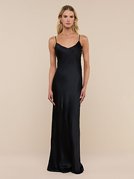 A woman stands against a plain white background wearing the Serita Silk Gown—a long, sleeveless black dress with thin straps, crafted from luxurious silk charmeuse.