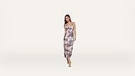 Woman wearing a sleeveless, floral-patterned midi dress and sandals stands against a plain white background.