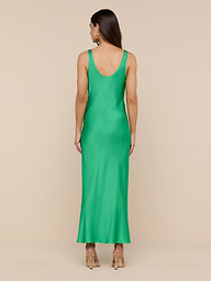 A woman stands facing away against a plain white background, wearing the sleeveless, ankle-length Akiya Satin Maxi Dress in island green paired with beige heels.