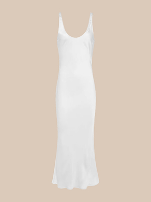 The Akiya Satin Maxi Dress is a sleeveless, white bias-cut tank dress with a scoop neckline and slightly flared hem, shown on a beige background.