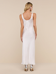 A woman with long blonde hair, wearing the Akiya Satin Maxi Dress and black heels, stands facing away from the camera against a plain white background.