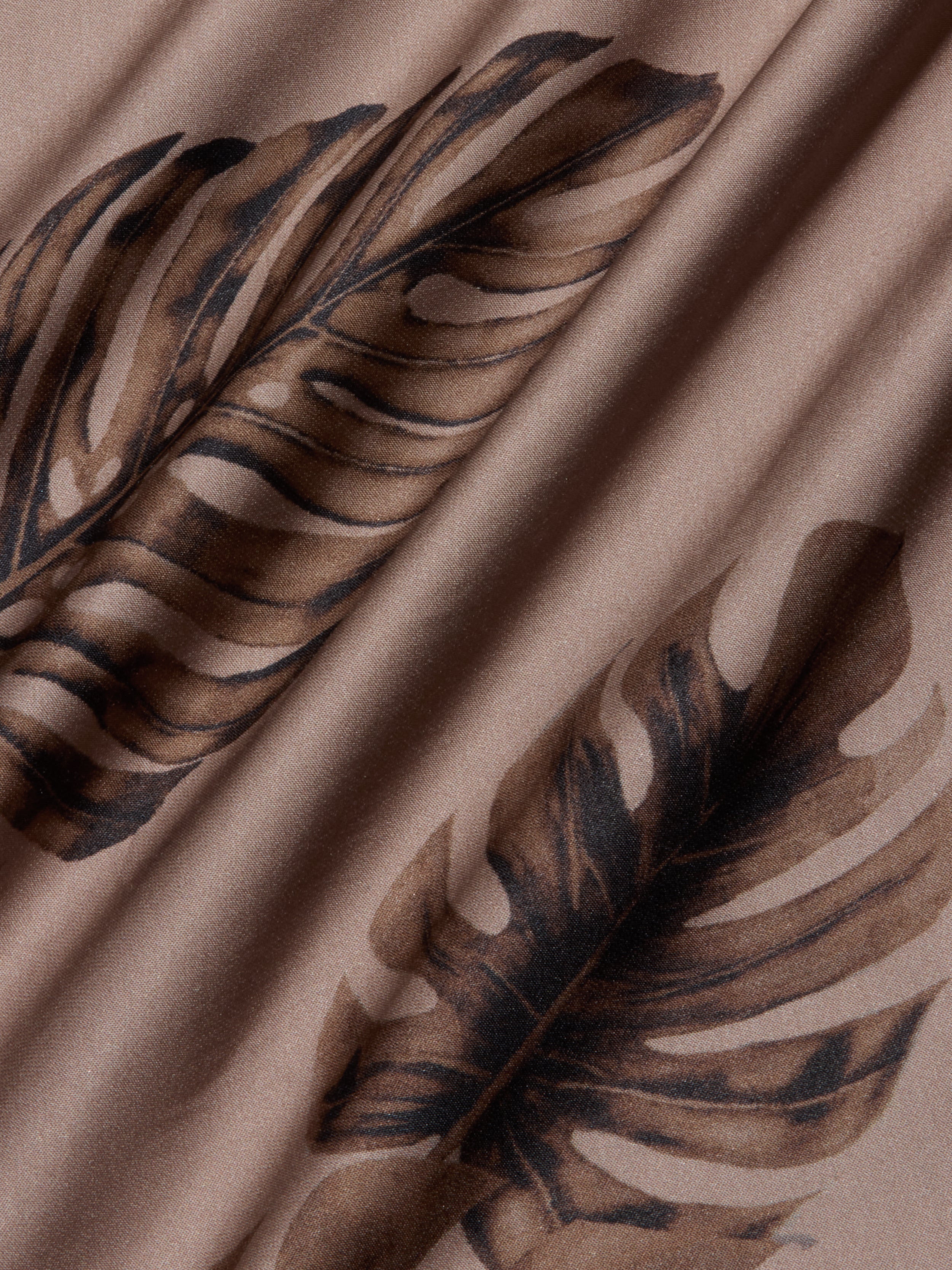 Close-up of the Akiya Satin Maxi Dress in beige, featuring a brown palm leaf print, with soft folds and a smooth, bias-cut satin texture.