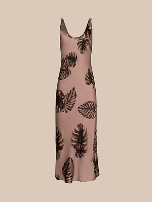 The Akiya Satin Maxi Dress is a sleeveless, light brown maxi with a scoop neckline and dark brown palm leaf print—bias-cut for elegance and shown on a beige background, making it an ideal day-to-night look.