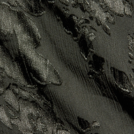 Close-up of textured dark fabric with raised, shiny floral or leaf patterns and a subtle sheen. The material features an embossed or jacquard weave design, similar to those found in the Christine Burnout Satin Gown.