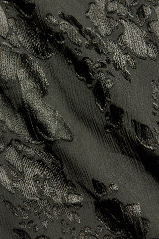 Close-up of the Christine Burnout Satin Gown’s black jacquard fabric, showcasing a raised, glossy floral pattern on a matte background. The subtly wavy texture adds depth and visual interest—ideal for this bias-cut gown that highlights the fabric’s elegant fluid drape.