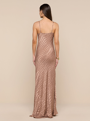 A woman with long, straight hair stands against a beige background, wearing the form-fitting Christine Burnout Satin Dress in rose gold with thin straps and a textured, scale-like pattern.