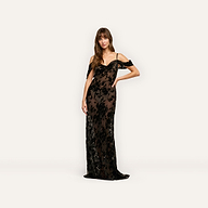 A woman wearing the Kenna Velvet Gown, a floor-length, off-the-shoulder black dress with a sheer floral overlay in burnout velvet.