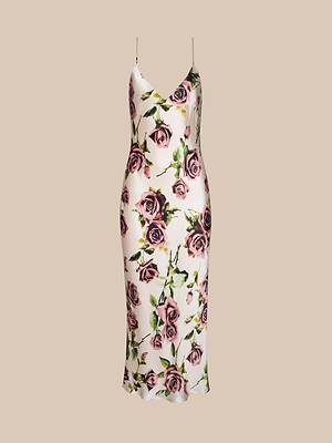 The Seridie Silk Slip Dress is a sleeveless, V-neck slip dress with thin spaghetti straps, a bias-cut silhouette, and a rose print featuring pink and purple roses with green leaves on a light beige background.