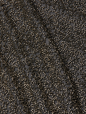 Close-up of black fabric from the Inori Beaded Mini Dress, featuring intricate gold bead embroidery in swirling, organic patterns. The densely packed beads create a textured, shimmering surface—perfect for making a statement.