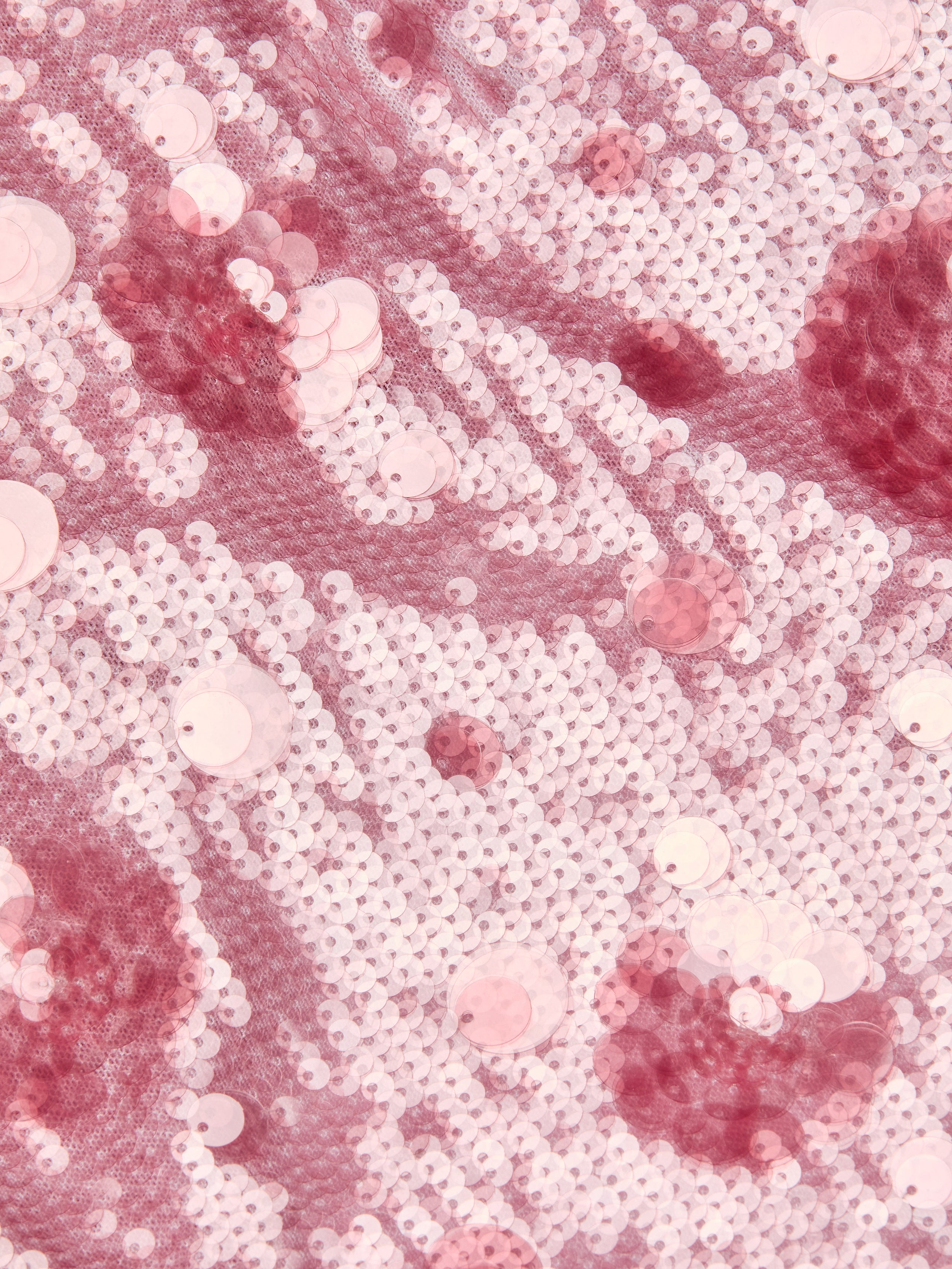 Close-up of shimmering pink and white sequins sewn onto fabric, creating a sparkling, textured pattern with light and dark pink circular shapes reminiscent of florals—perfect for making an eye-catching Karma Sequin Maxi Dress.