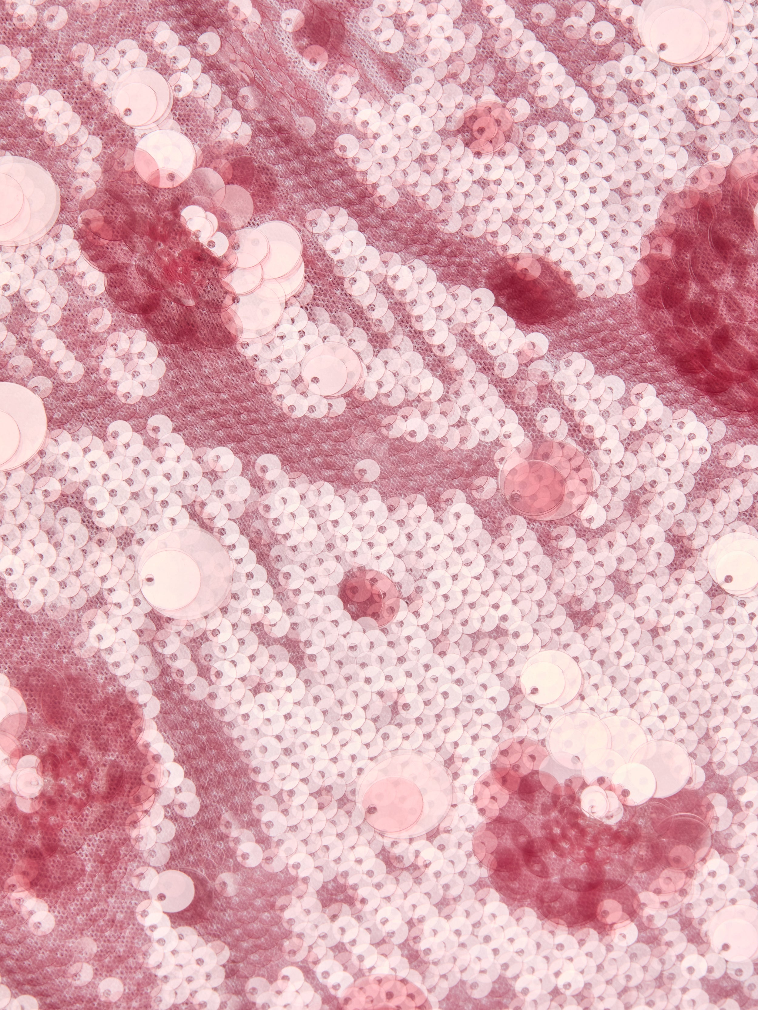 Close-up of shimmering pink and white sequins sewn onto fabric, creating a sparkling, textured pattern with light and dark pink circular shapes reminiscent of florals—perfect for making an eye-catching Karma Sequin Maxi Dress.