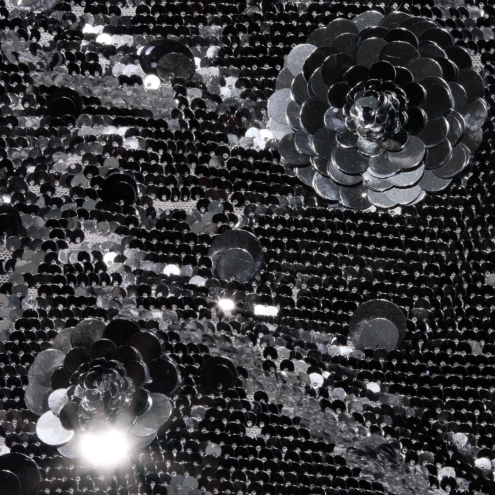 Black sequin fabric of the Karma Sequin Maxi Dress featuring two large, three-dimensional sequin flower appliqués.