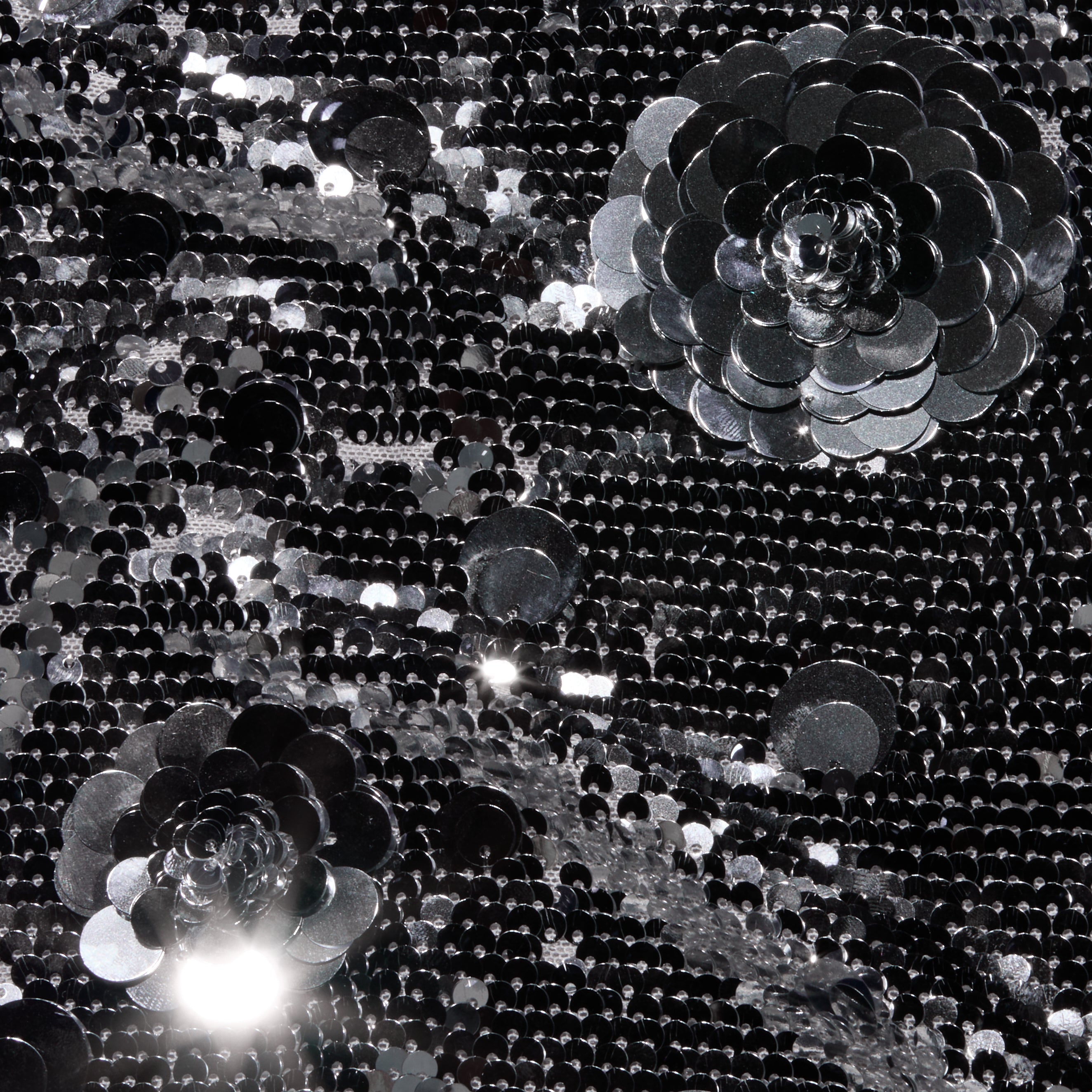 Black sequin fabric of the Karma Sequin Maxi Dress featuring two large, three-dimensional sequin flower appliqués.