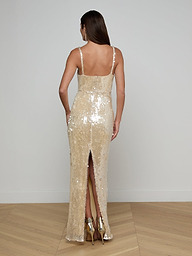 A woman with long brown hair is pictured from behind against a plain white background, wearing the sleeveless, backless Karma Sequin Maxi Dress featuring a back slit.