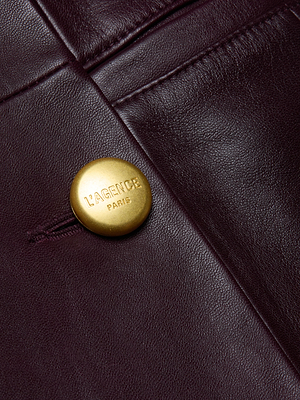 Close-up of the Tora Leather Blazer Dress in dark malbec lambskin, featuring a gold “LAGENCE PARIS” button and showcasing its exquisite stitching and rich texture.
