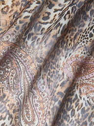 Gros plan sur le tissu de la robe en soie Charmaine, qui présente des motifs léopard et cachemire dans des tons beiges, bruns, noirs et rosés. Les plis souples créent des ombres et des textures, ce qui est idéal pour cette robe en soie coupée en biais et dotée de bretelles réglables.