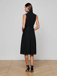 A woman stands facing away, wearing the Kylo Lace Shirt Dress with a belt and black high heels, against a plain light background.