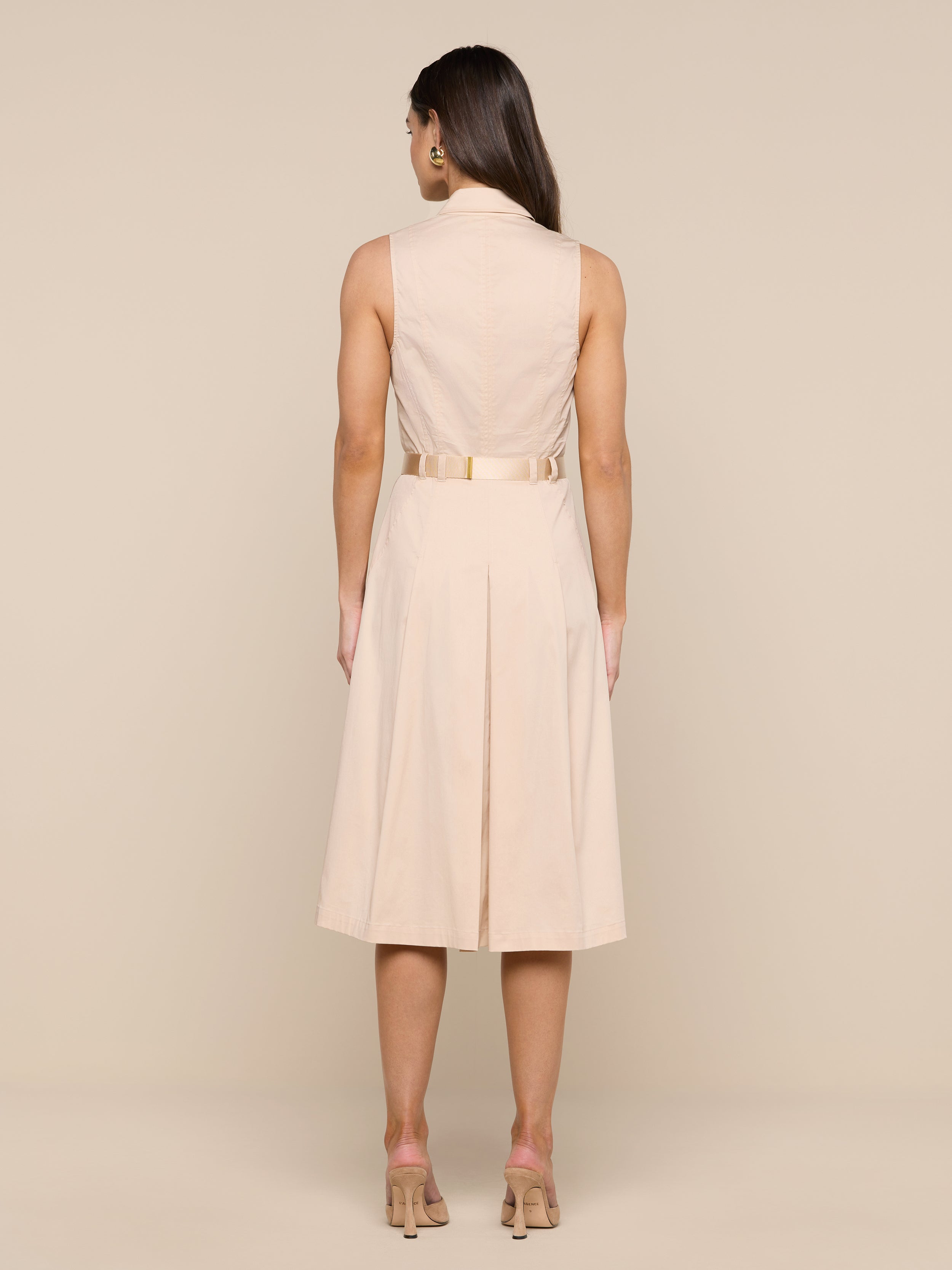 A woman stands facing away, wearing the Kylo Poplin Shirt Dress with nude heels, against a plain white background.