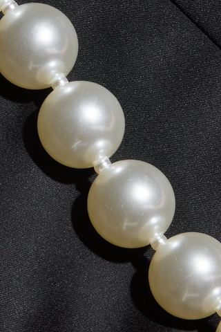 A close-up of large, round, white pearls strung together on a necklace, resting on a black fabric background—perfectly complementing the elegant Sutton Maxi Dress for a sophisticated evening look.
