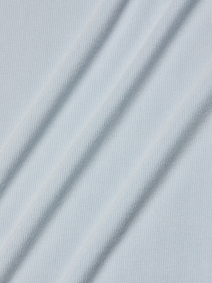 The Ellis Tank Dress features a light blue stretch rib fabric with subtle diagonal stripes and gentle shadows that hint at folds, creating a smooth and slightly ribbed texture.