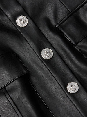 Close-up of the L'AGENCE Midy Vegan Leather Dress, a black mini with a structured fit, three crest-embossed silver buttons, and two flap pockets.
