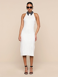 A woman wearing the Lilith Sequin Dress—a sleeveless, knee-length fitted party dress with a black collar—paired with black high heels and sunglasses, stands against a plain white background.