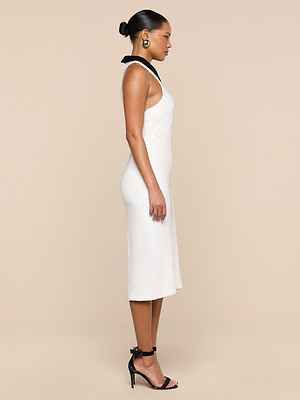 Woman in profile against a beige background wears the Lilith Sequin Dress with a black poplin collar, black high-heeled sandals, and statement earrings. Her hair is styled in a neat bun.