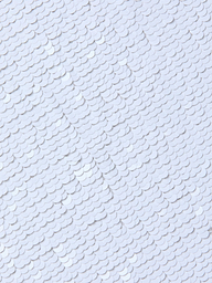 Close-up of overlapping white sequins on the Lilith Sequin Dress, creating a textured, shiny surface with a subtle fish-scale pattern on this fitted party piece.