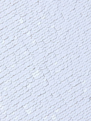 A close-up reveals the Lilith Sequin Dress’s textured white surface, adorned with neatly arranged, overlapping scale-like sequins that create a stunning, shimmering reflective pattern.