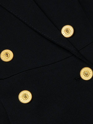 Close-up of the L'AGENCE Royalty Mini Dress in black two-way stretch fabric, featuring four gold lion-embossed buttons with a dotted circular border.